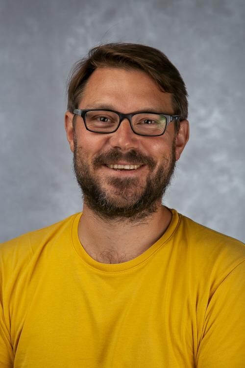 Portrettbilde av mann med briller og kort mørkt hår og skjegg. Foto - Klikk for stort bilde